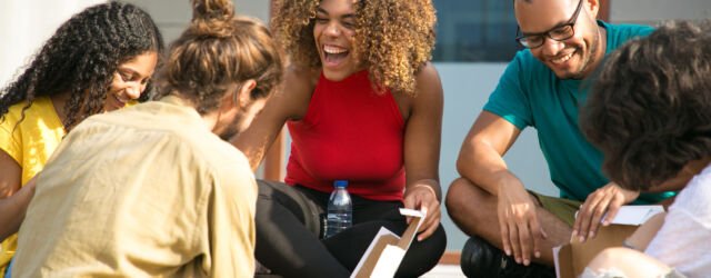 Happy joyful friends talking and laughing Happy joyful friends talking and laughing over outdoor lunch. Mix raced group of young people sitting on outdoor stairs and eating takeaway pizza from box. Mealtime outside concept